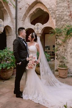 a bride and groom standing in front of an old building