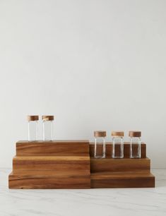 three small glass bottles sitting on top of a wooden stand next to eachother