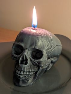 a candle that is on top of a plate with a skull in the middle of it