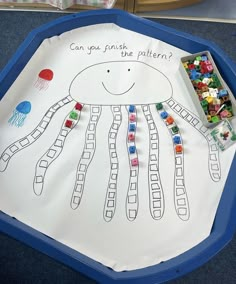 a child's drawing of a jellyfish on a paper plate with beads in it