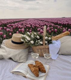 two croissants and a glass of wine on a table in front of a field of tulips