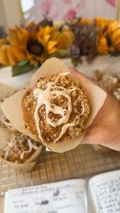 a person holding food in their hand with sunflowers in the backgroud