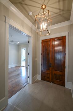 an empty room with two doors and a chandelier hanging from it's ceiling