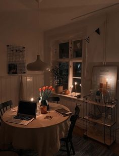 a laptop computer sitting on top of a wooden table next to a vase filled with flowers