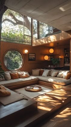 a living room filled with lots of furniture under a large window next to a tree