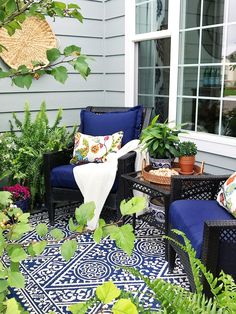 an outdoor patio with blue chairs and potted plants on the side of the house