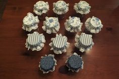 several cupcakes with blue and white designs on them sitting on a wooden table