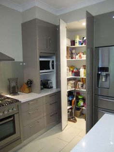 a kitchen with stainless steel appliances and white counter tops, along with open shelves in the middle