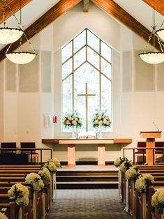 the inside of a church with pews and flowers on the alter, decorated for a wedding