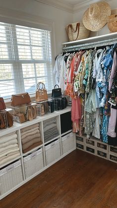 an organized closet with clothes and handbags on the shelves, along with wicker baskets