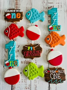 decorated cookies are arranged in the shape of fish on a white wooden background with words that read one, one, one, one, one