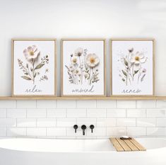 three framed flowers are hanging on the wall above a bathtub