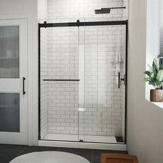 a bathroom with a white rug and black trimming on the shower door, toilet and bathtub