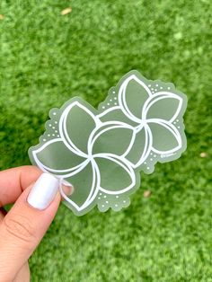 a person holding up a sticker with flowers on it in front of green grass