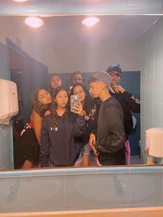 a group of people taking a selfie in a bathroom mirror