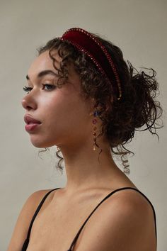 a woman with curly hair wearing a headband and looking off to the side in profile