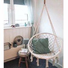 a white hanging chair next to a window