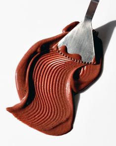 a spatula that is sitting on top of some red chocolate icing with a spoon sticking out of it