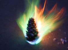 a pine cone is lit up with green and orange flames