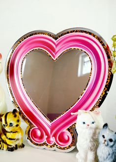 a heart shaped mirror sitting on top of a table next to figurines