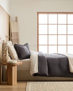 a bed with pillows and blankets next to a window