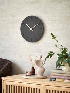 a clock on the wall above a table with some candles and bottles in front of it