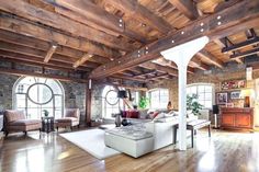 a large living room with wood floors and exposed ceilings