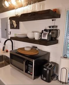 a microwave oven sitting on top of a counter next to a sink and coffee maker