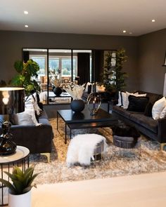 a living room filled with lots of furniture and plants on top of a rug in front of a fire place