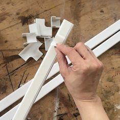 a person is working on an unfinished piece of furniture with white paint and plastic tools