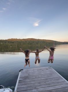 three kids jumping off a dock into the water