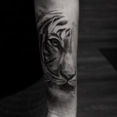 a black and white photo of a tiger's face on the left forearm tattoo