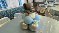 an elephant is sitting on top of some blue and silver balloons at a baby's first birthday party