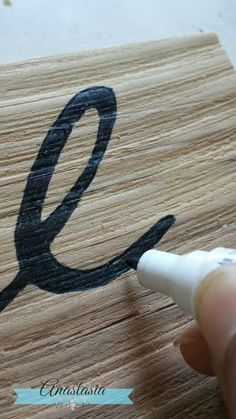 someone is drawing the letter e on a piece of wood