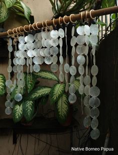 a close up of a wind chime hanging from a metal pole near a potted plant