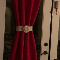 a red curtain with a white flower on it in front of a door that is open