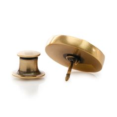 a pair of gold plated cufflinks and a small screwdriver on a white background