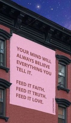 a pink sign hanging from the side of a brick building that says, your mind will always believe everything you tell it