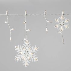 three snowflakes are hanging from a wire with lights on them, and one is upside down