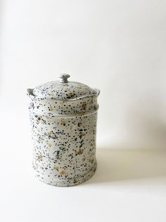 a white and black speckled canister sitting on top of a table