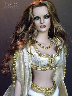 a doll dressed in gold and white is posed for the camera with her hair blowing back