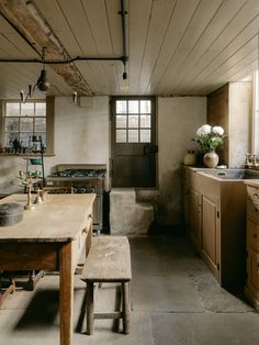 an old fashioned kitchen with wooden cabinets and counter tops, along with a bench in front of the sink