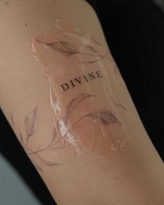 a woman's arm with a tattoo that reads divine and leaves on the side