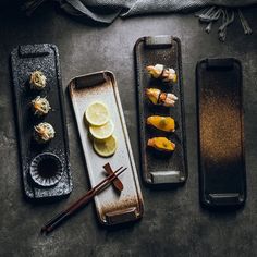 three trays filled with sushi and chopsticks on top of a table