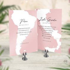 a pink and white wedding card on top of a wooden table with flowers in the background