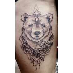 a bear tattoo on the back of a woman's lower thigh, with roses around it