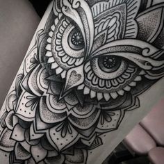 an owl tattoo on the thigh with intricate details in black and grey ink, done by person