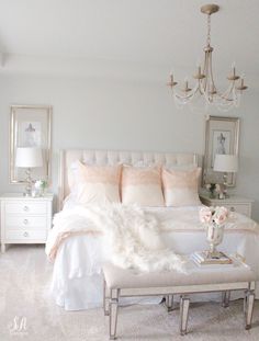 a white bedroom with chandelier, bed and two nightstands in the corner