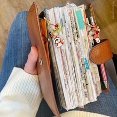 a person holding a wallet filled with lots of cards and money in their left hand