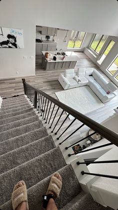 someone's feet are on the stairs in front of a living room and kitchen